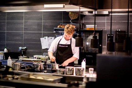Restaurant kitchen staff member working near commercial cooking equipment