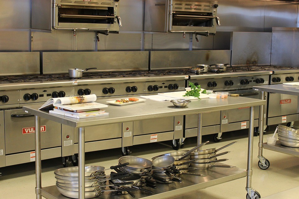 Commercial kitchen cook line with stainless steel prep tables and cooking equipment