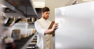 Restaurant cook inspecting a commercial walk-in cooler before gasket replacement