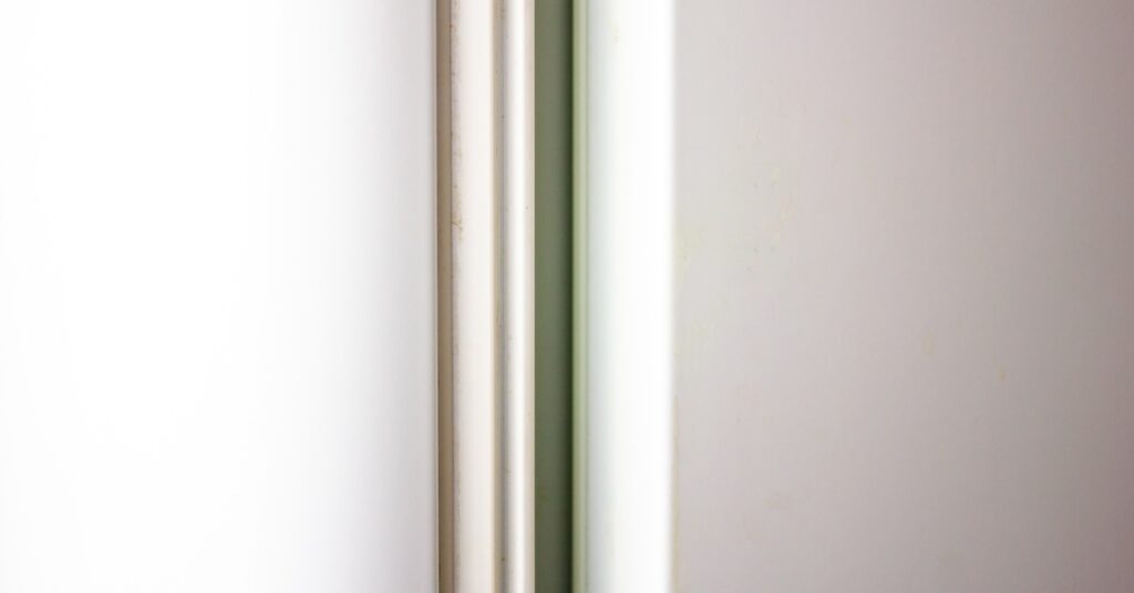 A close-up of a white rubber gasket attached to the side of a white door with a black trim on the edge.